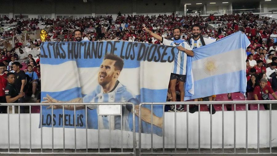 Pendukung Argentina mengibarkan bendera bergambar bintang sepak bola Lionel Messi sebelum pertandingan sepak bola persahabatan melawan Indonesia di Stadion Utama Gelora Bung Karno di Jakarta, Indonesia, Senin, 19 Juni 2023. (AP Photo/Achmad Ibrahim)
