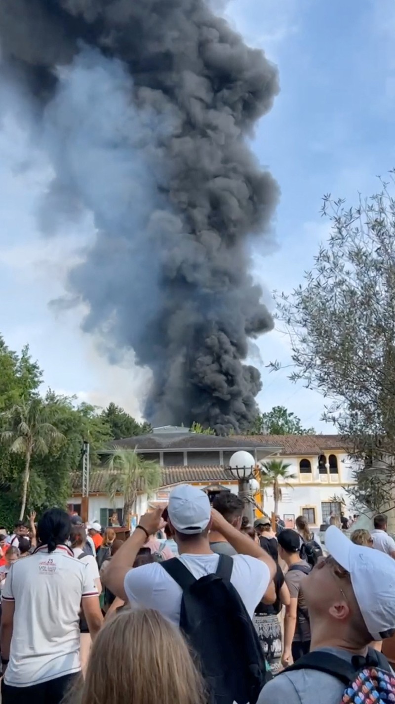 Pengunjung melihat asap yang mengepul di atas 'Europa-Park' di Rust, Jerman, Senin, 19 Juni 2023. Kebakaran besar terjadi di sebuah taman hiburan di barat daya Jerman, dengan asap hitam besar terlihat dari jauh. (zema-medien/dpa via AP)