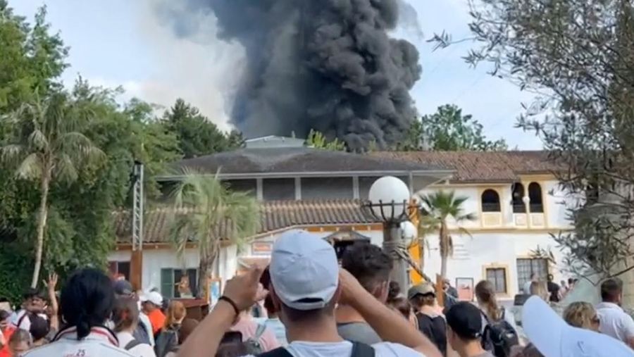 Pengunjung melihat asap yang mengepul di atas 'Europa-Park' di Rust, Jerman, Senin, 19 Juni 2023. Kebakaran besar terjadi di sebuah taman hiburan di barat daya Jerman, dengan asap hitam besar terlihat dari jauh. (zema-medien/dpa via AP)