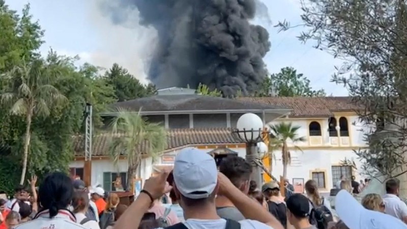 Pengunjung melihat asap yang mengepul di atas 'Europa-Park' di Rust, Jerman, Senin, 19 Juni 2023. Kebakaran besar terjadi di sebuah taman hiburan di barat daya Jerman, dengan asap hitam besar terlihat dari jauh. (zema-medien/dpa via AP)