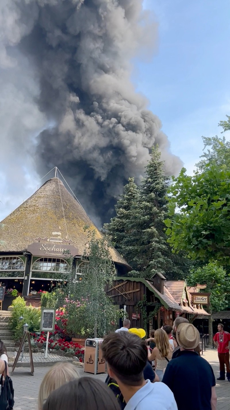 Pengunjung melihat asap yang mengepul di atas 'Europa-Park' di Rust, Jerman, Senin, 19 Juni 2023. Kebakaran besar terjadi di sebuah taman hiburan di barat daya Jerman, dengan asap hitam besar terlihat dari jauh. (zema-medien/dpa via AP)