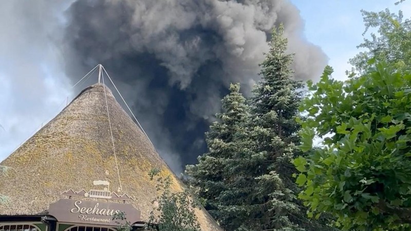 Pengunjung melihat asap yang mengepul di atas 'Europa-Park' di Rust, Jerman, Senin, 19 Juni 2023. Kebakaran besar terjadi di sebuah taman hiburan di barat daya Jerman, dengan asap hitam besar terlihat dari jauh. (zema-medien/dpa via AP)