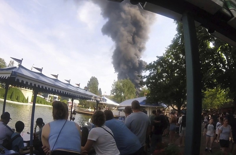 Pengunjung melihat asap yang mengepul di atas 'Europa-Park' di Rust, Jerman, Senin, 19 Juni 2023. Kebakaran besar terjadi di sebuah taman hiburan di barat daya Jerman, dengan asap hitam besar terlihat dari jauh. (zema-medien/dpa via AP)