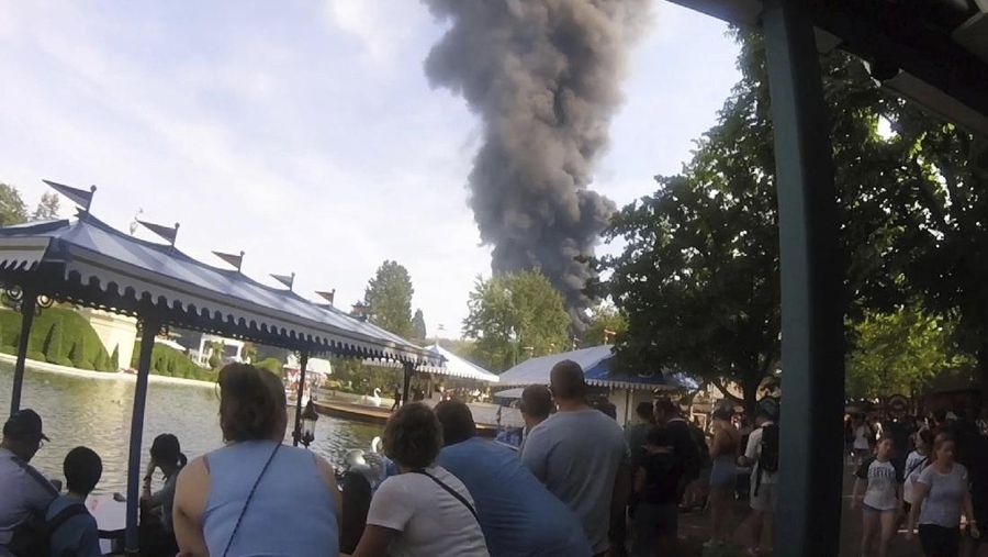 Pengunjung melihat asap yang mengepul di atas 'Europa-Park' di Rust, Jerman, Senin, 19 Juni 2023. Kebakaran besar terjadi di sebuah taman hiburan di barat daya Jerman, dengan asap hitam besar terlihat dari jauh. (zema-medien/dpa via AP)