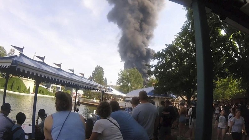 Pengunjung melihat asap yang mengepul di atas 'Europa-Park' di Rust, Jerman, Senin, 19 Juni 2023. Kebakaran besar terjadi di sebuah taman hiburan di barat daya Jerman, dengan asap hitam besar terlihat dari jauh. (zema-medien/dpa via AP)