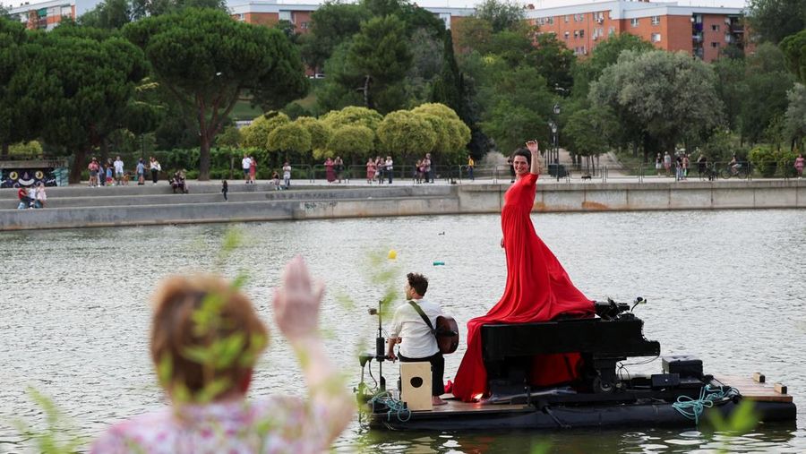 Pianis asal Prancis Violette Prevost menghibur ratusan warga di danau Pradolongo, Usera, Madrid, Spanyol. (REUTERS/Isabel Infantes)