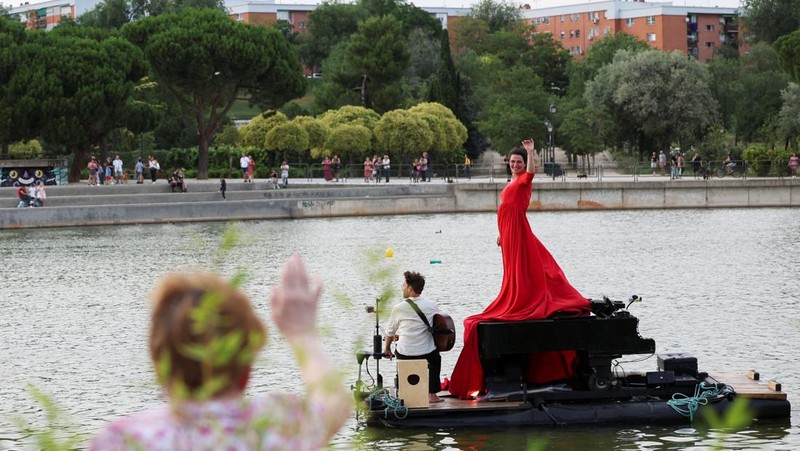 Pianis asal Prancis Violette Prevost menghibur ratusan warga di danau Pradolongo, Usera, Madrid, Spanyol. (REUTERS/Isabel Infantes)