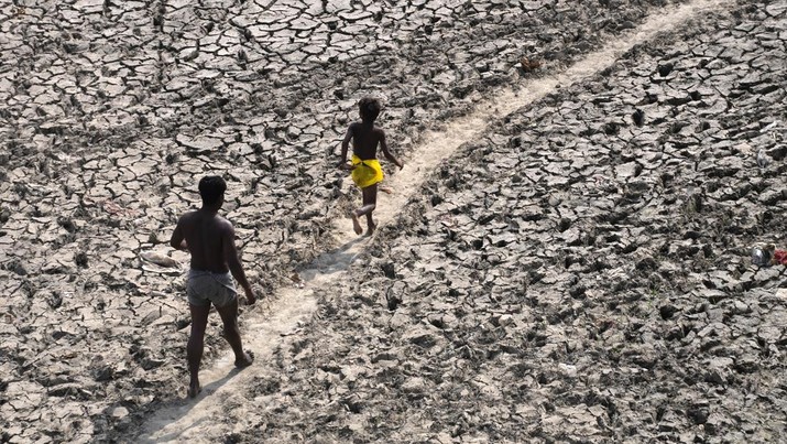 Seorang pria dan seorang anak laki-laki berjalan melintasi dasar sungai Yamuna yang hampir kering setelah cuaca panas di New Delhi, India, Senin, 2 Mei 2022. (File Photo/AP Photo/Manish Swarup)