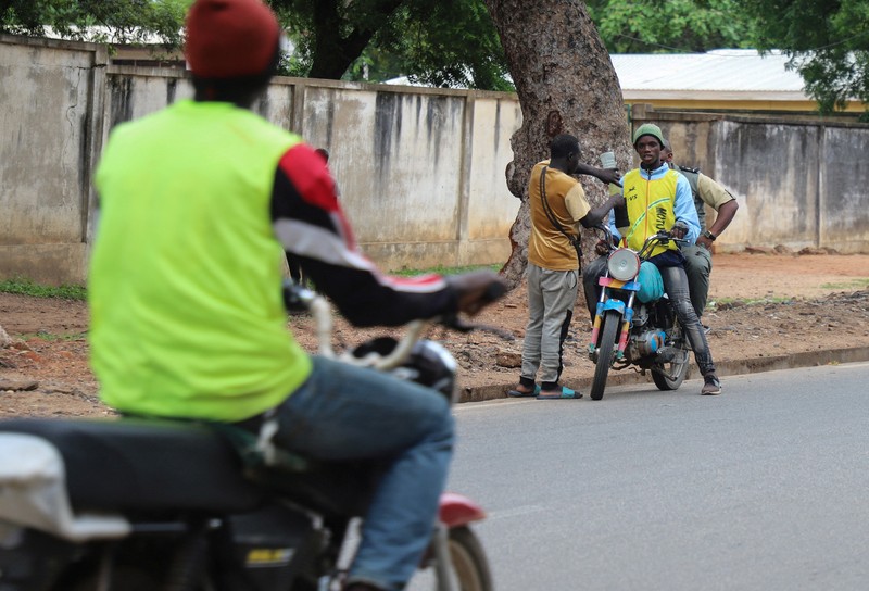 NIGERIA-PETROL/NEIGHBOURS A cameroon customs officer sits on a motorcycle taxi that's getting refuelled with smuggled Nigerian fuel in Garoua, Cameroon June 21, 2023. REUTERS/Desire Danga Essigue