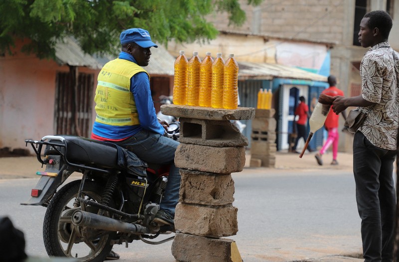 NIGERIA-PETROL/NEIGHBOURS A cameroon customs officer sits on a motorcycle taxi that's getting refuelled with smuggled Nigerian fuel in Garoua, Cameroon June 21, 2023. REUTERS/Desire Danga Essigue