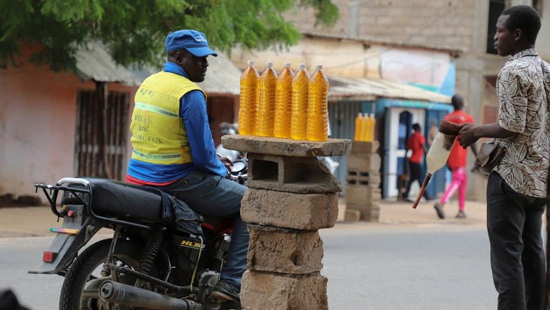 A cameroon customs officer sits on a motorcycle taxi that's getting refuelled with smuggled Nigerian fuel in Garoua, Cameroon June 21, 2023. REUTERS/Desire Danga Essigue