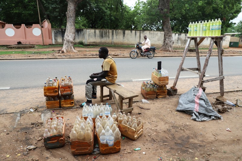 NIGERIA-PETROL/NEIGHBOURS A cameroon customs officer sits on a motorcycle taxi that's getting refuelled with smuggled Nigerian fuel in Garoua, Cameroon June 21, 2023. REUTERS/Desire Danga Essigue