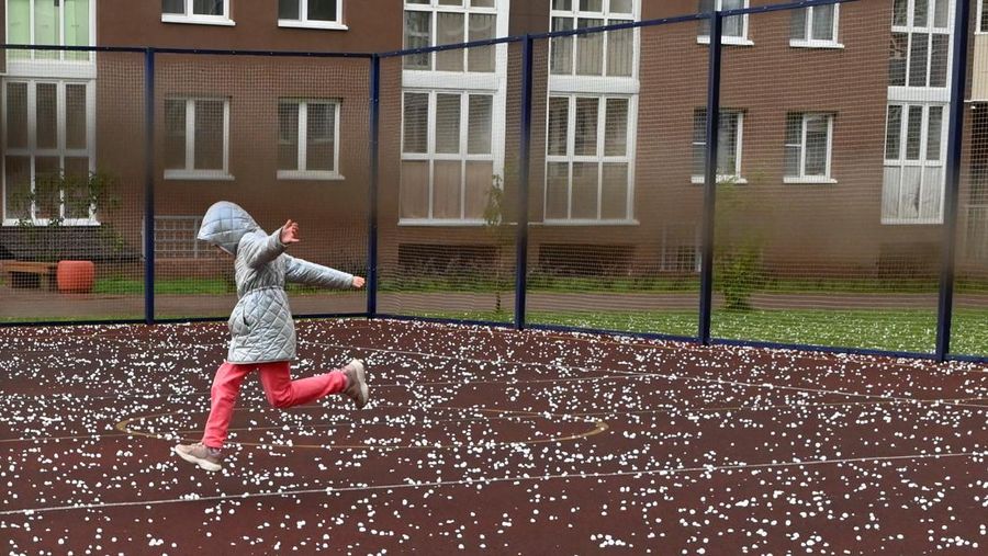 Seorang anak berlari melintasi lapangan olahraga yang tertutup hujan es menyusul badai hujan es di kota Siberia, Omsk, Rusia, 27 Juni 2023. (REUTERS/Alexey Malgavko)
