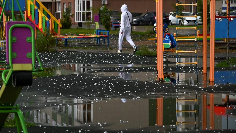 Seorang penduduk setempat memperagakan hujan es setelah badai es di kota Siberia, Omsk, Rusia, 27 Juni 2023. (REUTERS/Alexey Malgavko)