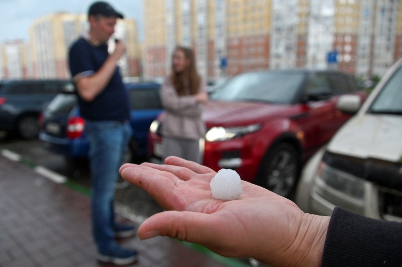 Seorang penduduk setempat memperagakan hujan es setelah badai es di kota Siberia, Omsk, Rusia, 27 Juni 2023. (REUTERS/Alexey Malgavko)