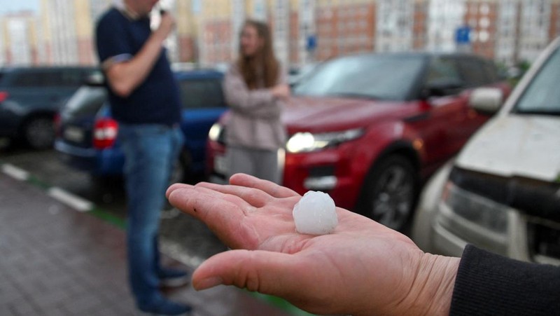 Seorang penduduk setempat memperagakan hujan es setelah badai es di kota Siberia, Omsk, Rusia, 27 Juni 2023. (REUTERS/Alexey Malgavko)