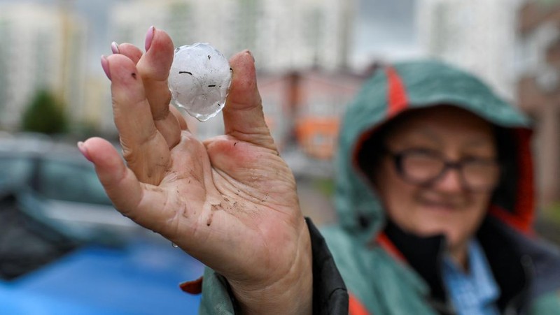 Seorang penduduk setempat memperagakan hujan es setelah badai es di kota Siberia, Omsk, Rusia, 27 Juni 2023. (REUTERS/Alexey Malgavko)