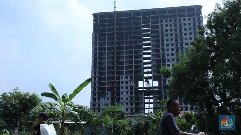 Warga melewati bangunan Apartemen Point 8 yang terbengkalai di kawasan Daan Mogot, Jakarta, Selasa (27/6/2023). (CNBC Indonesia/Tri Susilo)