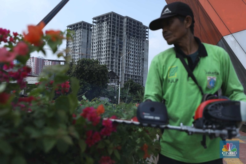 Warga melewati bangunan Apartemen Point 8 yang terbengkalai di kawasan Daan Mogot, Jakarta, Selasa (27/6/2023). (CNBC Indonesia/Tri Susilo)