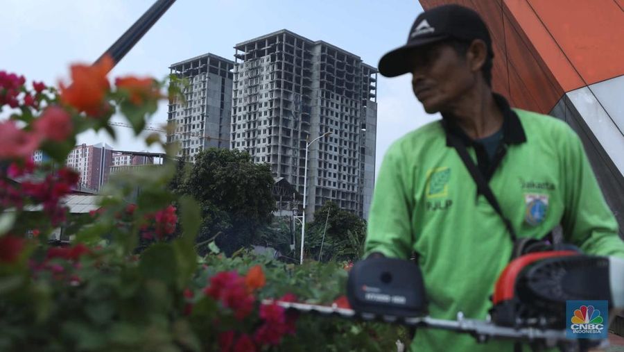 Warga melewati bangunan Apartemen Point 8 yang terbengkalai di kawasan Daan Mogot, Jakarta, Selasa (27/6/2023). (CNBC Indonesia/Tri Susilo)