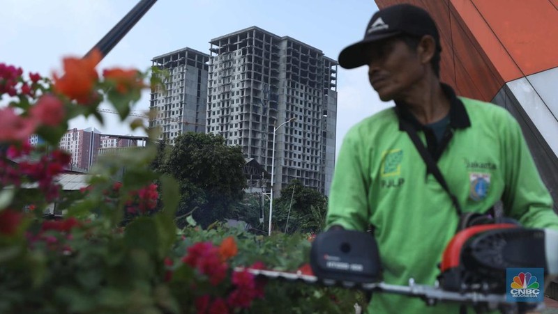 Warga melewati bangunan Apartemen Point 8 yang terbengkalai di kawasan Daan Mogot, Jakarta, Selasa (27/6/2023). (CNBC Indonesia/Tri Susilo)