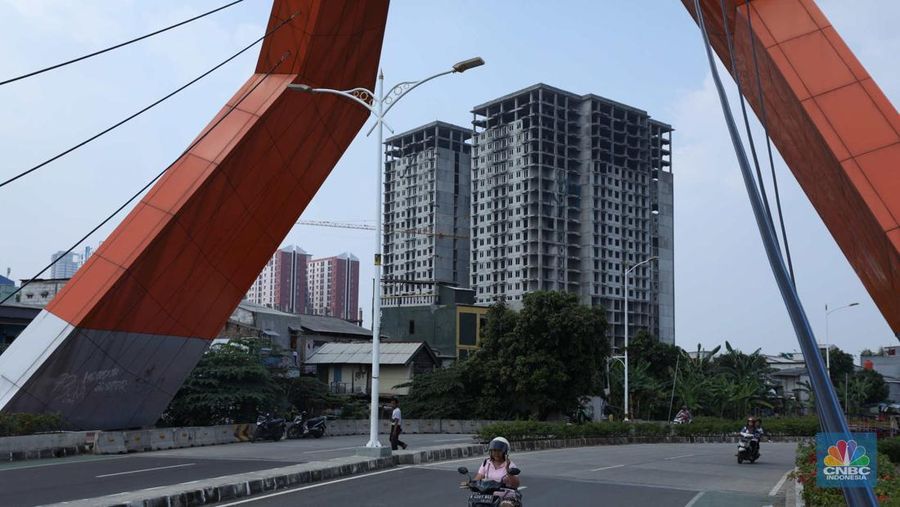 Warga melewati bangunan Apartemen Point 8 yang terbengkalai di kawasan Daan Mogot, Jakarta, Selasa (27/6/2023). (CNBC Indonesia/Tri Susilo)