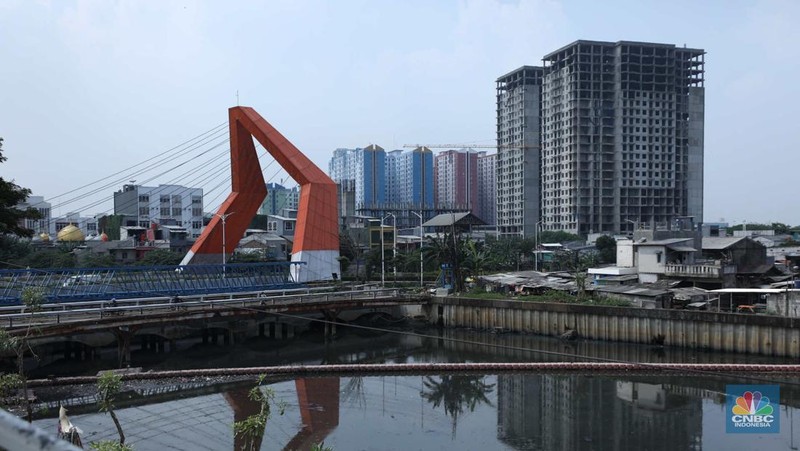 Warga melewati bangunan Apartemen Point 8 yang terbengkalai di kawasan Daan Mogot, Jakarta, Selasa (27/6/2023). (CNBC Indonesia/Tri Susilo)