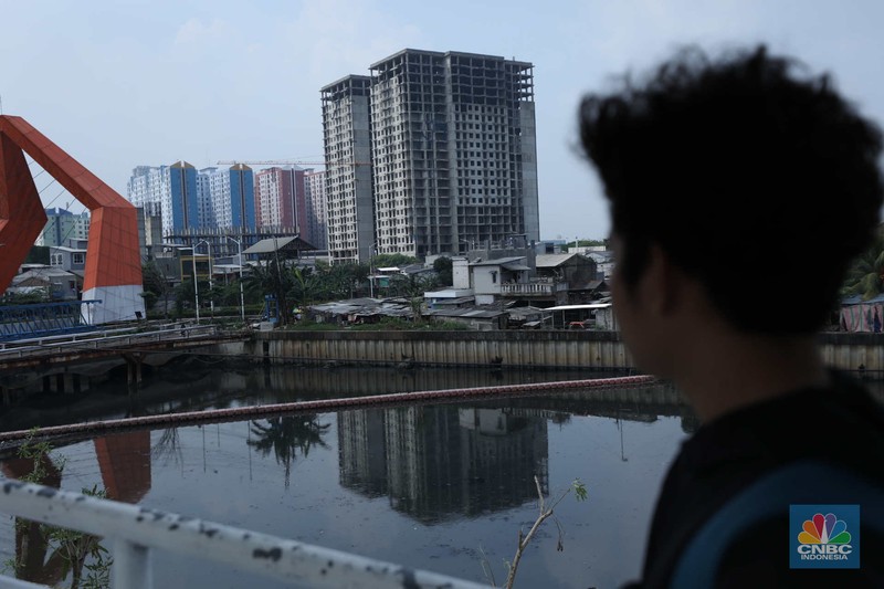 Warga melewati bangunan Apartemen Point 8 yang terbengkalai di kawasan Daan Mogot, Jakarta, Selasa (27/6/2023). (CNBC Indonesia/Tri Susilo)