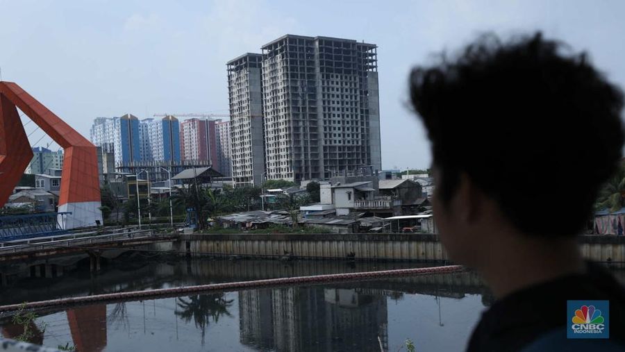 Warga melewati bangunan Apartemen Point 8 yang terbengkalai di kawasan Daan Mogot, Jakarta, Selasa (27/6/2023). (CNBC Indonesia/Tri Susilo)