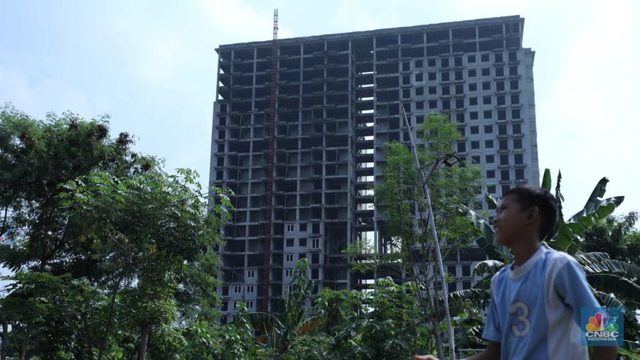 Warga melewati bangunan Apartemen Point 8 yang terbengkalai di kawasan Daan Mogot, Jakarta, Selasa (27/6/2023). (CNBC Indonesia/Tri Susilo)