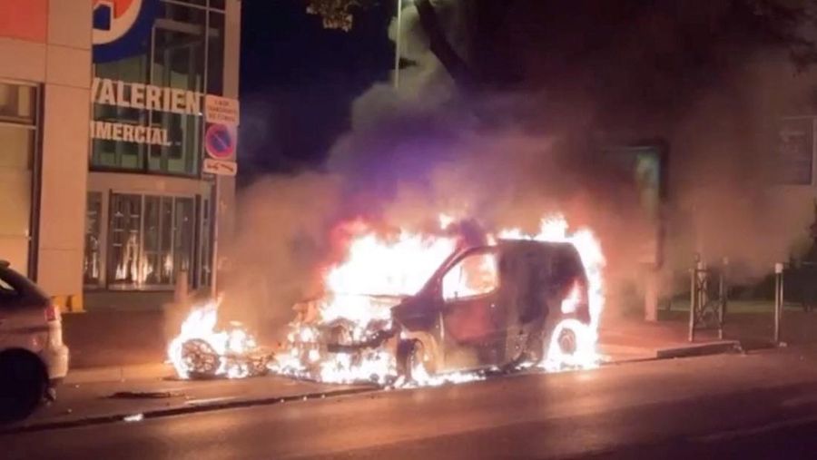 Sebuah foto memperlihatkan mobil yang terbakar di sela-sela demonstrasi di Nanterre, sebelah barat Paris, pada (27/6/2023) waktu setempat setelah polisi Prancis membunuh seorang remaja yang menolak berhenti untuk pemeriksaan lalu lintas di kota tersebut. (Eva Gueye via REUTERS/EVA GUEYE)