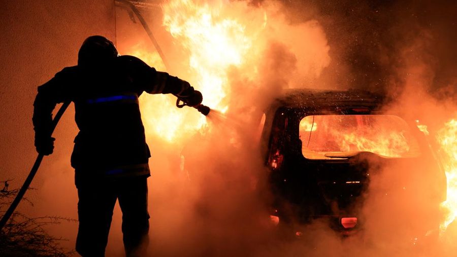 A French firefighter works to extinguish a burning car during Kerusuhan akibat seorang remaja ditembak mati oleh Polisi di pinggiran kota Paris, Prancis, Minggu (2/7/2023).
(REUTERS/Pascal Rossignol)