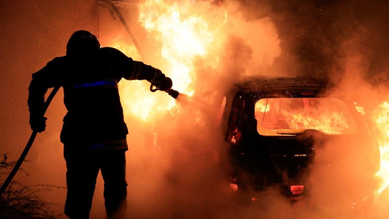 A French firefighter works to extinguish a burning car during Kerusuhan akibat seorang remaja ditembak mati oleh Polisi di pinggiran kota Paris, Prancis, Minggu (2/7/2023).
(REUTERS/Pascal Rossignol)