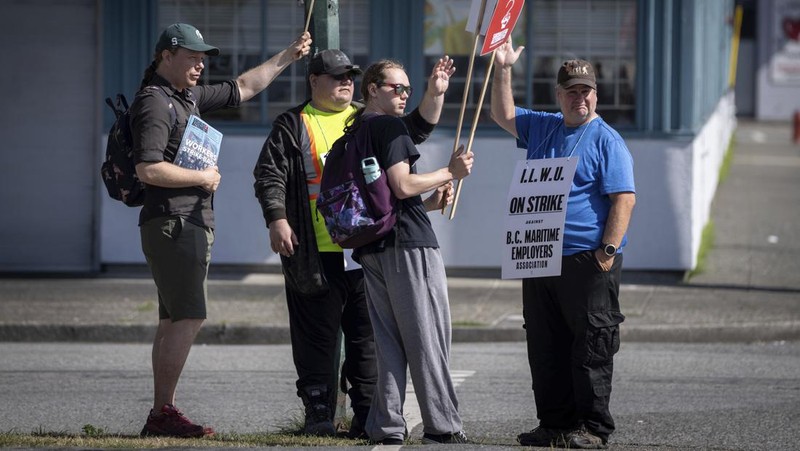 International Longshore and Warehouse Union workers picket outside of the BC Maritime Employers Association Dispatch Center after a 72 hour strike notice and no agreement made on the bargaining table in Vancouver, on Saturday, July 1, 2023. (Ethan Cairns /The Canadian Press via AP)