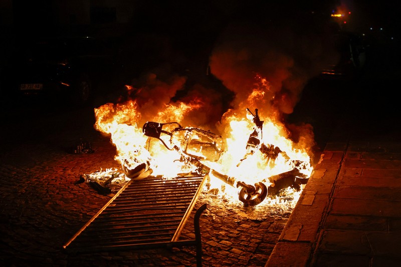 A French firefighter works to extinguish a burning car during Kerusuhan akibat seorang remaja ditembak mati oleh Polisi di pinggiran kota Paris, Prancis, Minggu (2/7/2023).
(REUTERS/Pascal Rossignol)