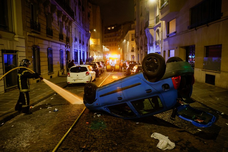 A French firefighter works to extinguish a burning car during Kerusuhan akibat seorang remaja ditembak mati oleh Polisi di pinggiran kota Paris, Prancis, Minggu (2/7/2023).
(REUTERS/Pascal Rossignol)