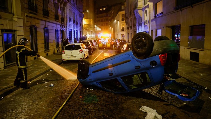 A French firefighter works to extinguish a burning car during Kerusuhan akibat seorang remaja ditembak mati oleh Polisi di pinggiran kota Paris, Prancis, Minggu (2/7/2023).
(REUTERS/Pascal Rossignol)