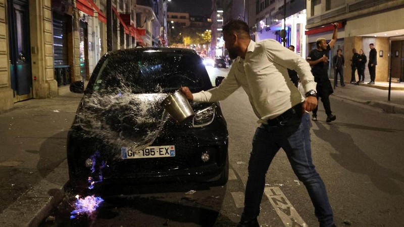 A French firefighter works to extinguish a burning car during Kerusuhan akibat seorang remaja ditembak mati oleh Polisi di pinggiran kota Paris, Prancis, Minggu (2/7/2023).
(REUTERS/Pascal Rossignol)
