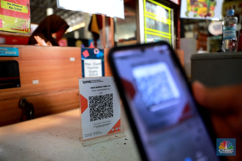 Pembeli melakukan transkasi pembayaran qris di Pasar Santa, Jakarta, Senin, (3/7). Pembeli melakukan transkasi pembayaran qris di Pasar Santa, Jakarta, Senin, (3/7). (CNBC Indonesia/Muhammad Sabki)