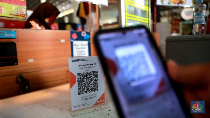 Pembeli melakukan transkasi pembayaran qris di Pasar Santa, Jakarta, Senin, (3/7). (CNBC Indonesia/Muhammad Sabki)