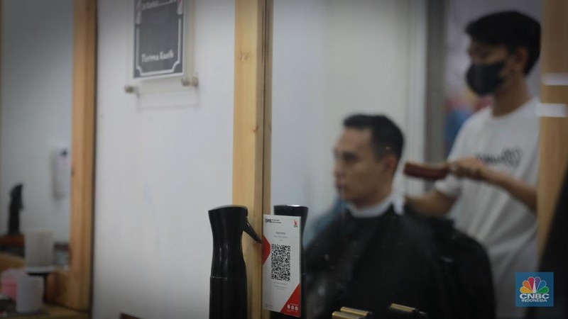 Pembeli melakukan transkasi pembayaran qris di Pasar Santa, Jakarta, Senin, (3/7). (CNBC Indonesia/Muhammad Sabki)