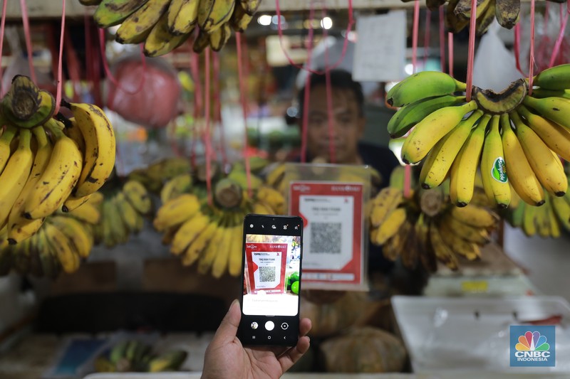Pembeli melakukan transkasi pembayaran qris di Pasar Santa, Jakarta, Senin, (3/7). Pembeli melakukan transkasi pembayaran qris di Pasar Santa, Jakarta, Senin, (3/7). (CNBC Indonesia/Muhammad Sabki)