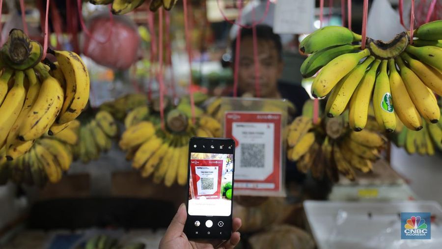 Pembeli melakukan transkasi pembayaran qris di Pasar Santa, Jakarta, Senin, (3/7). (վ/Muhammad Sabki)