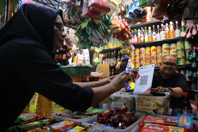 Pembeli melakukan transkasi pembayaran qris di Pasar Santa, Jakarta, Senin, (3/7). (CNBC Indonesia/Muhammad Sabki)