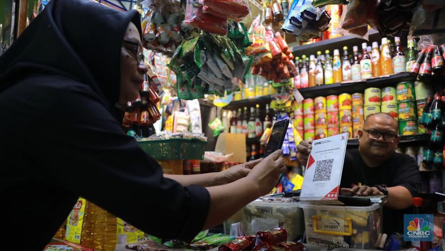 Pembeli melakukan transkasi pembayaran qris di Pasar Santa, Jakarta, Senin, (3/7). (վ/Muhammad Sabki)