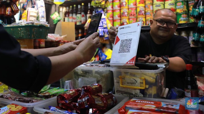 Pembeli melakukan transkasi pembayaran qris di Pasar Santa, Jakarta, Senin, (3/7). (CNBC Indonesia/Muhammad Sabki)