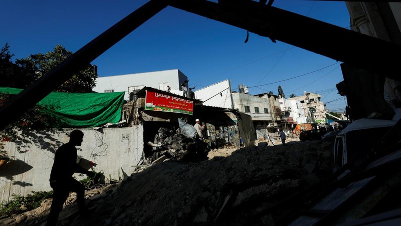 Seorang wanita Palestina duduk di depan sebuah bangunan yang rusak setelah penarikan tentara Israel dari kamp Jenin, di Jenin, di Tepi Barat yang diduduki Israel 5 Juli 2023. (REUTERS/Mohamad Torokman)