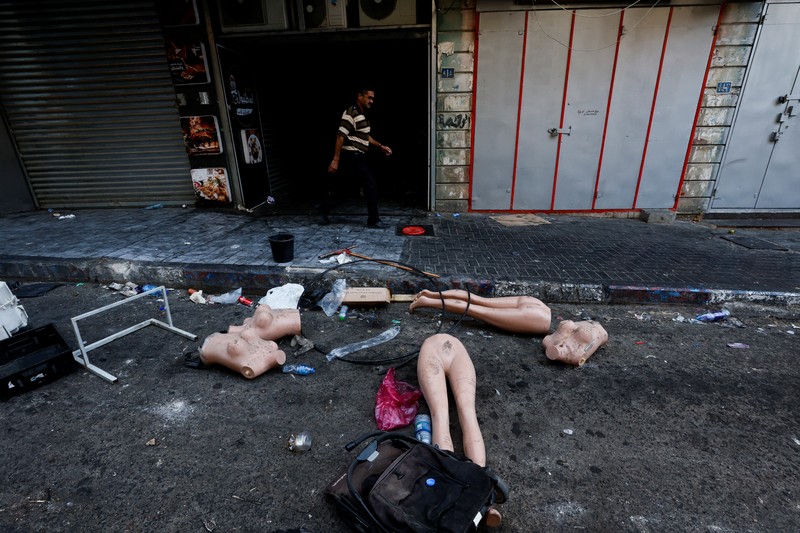 Seorang wanita Palestina duduk di depan sebuah bangunan yang rusak setelah penarikan tentara Israel dari kamp Jenin, di Jenin, di Tepi Barat yang diduduki Israel 5 Juli 2023. (REUTERS/Mohamad Torokman)