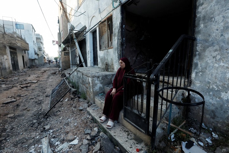 Seorang wanita Palestina duduk di depan sebuah bangunan yang rusak setelah penarikan tentara Israel dari kamp Jenin, di Jenin, di Tepi Barat yang diduduki Israel 5 Juli 2023. Seorang wanita Palestina duduk di depan sebuah bangunan yang rusak setelah penarikan tentara Israel dari kamp Jenin, di Jenin, di Tepi Barat yang diduduki Israel 5 Juli 2023. (REUTERS/Mohamad Torokman)