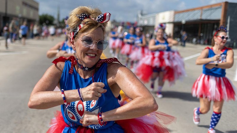 Masyarakat Amerika Serikat (AS) merayakan parade Fourth of July dengan membawa bendera di Westmont, Suburb of Johnstown, Selasa (4/7/2023). (REUTERS/BRIAN SNYDER)